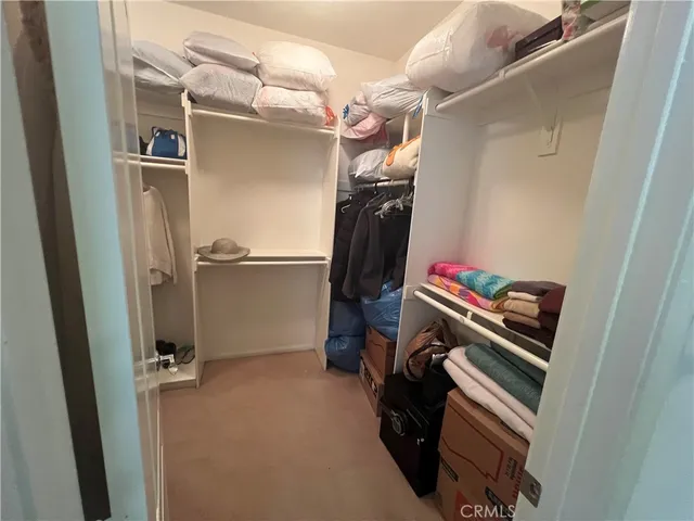 a view of walk in closet with clothes and shoes