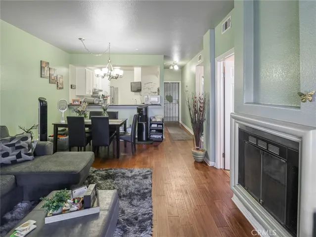 a living room with furniture a fireplace and a dining table with wooden floor