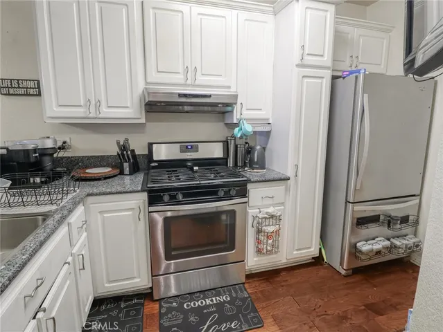 a kitchen with stainless steel appliances granite countertop a refrigerator stove and white cabinets
