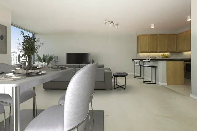 a living room with stainless steel appliances furniture a rug and a kitchen view