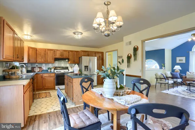 a view of a dining room with furniture a kitchen and chandelier