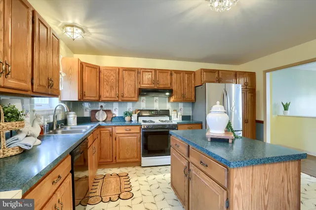 a kitchen with stainless steel appliances granite countertop a sink refrigerator stove and microwave