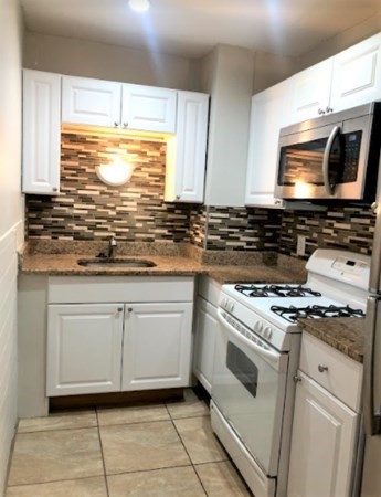 10 Fourth St Place, Unit 1 Cambridge, MA 02141 - Photo 2 of 6 a kitchen with granite countertop white cabinets and appliances