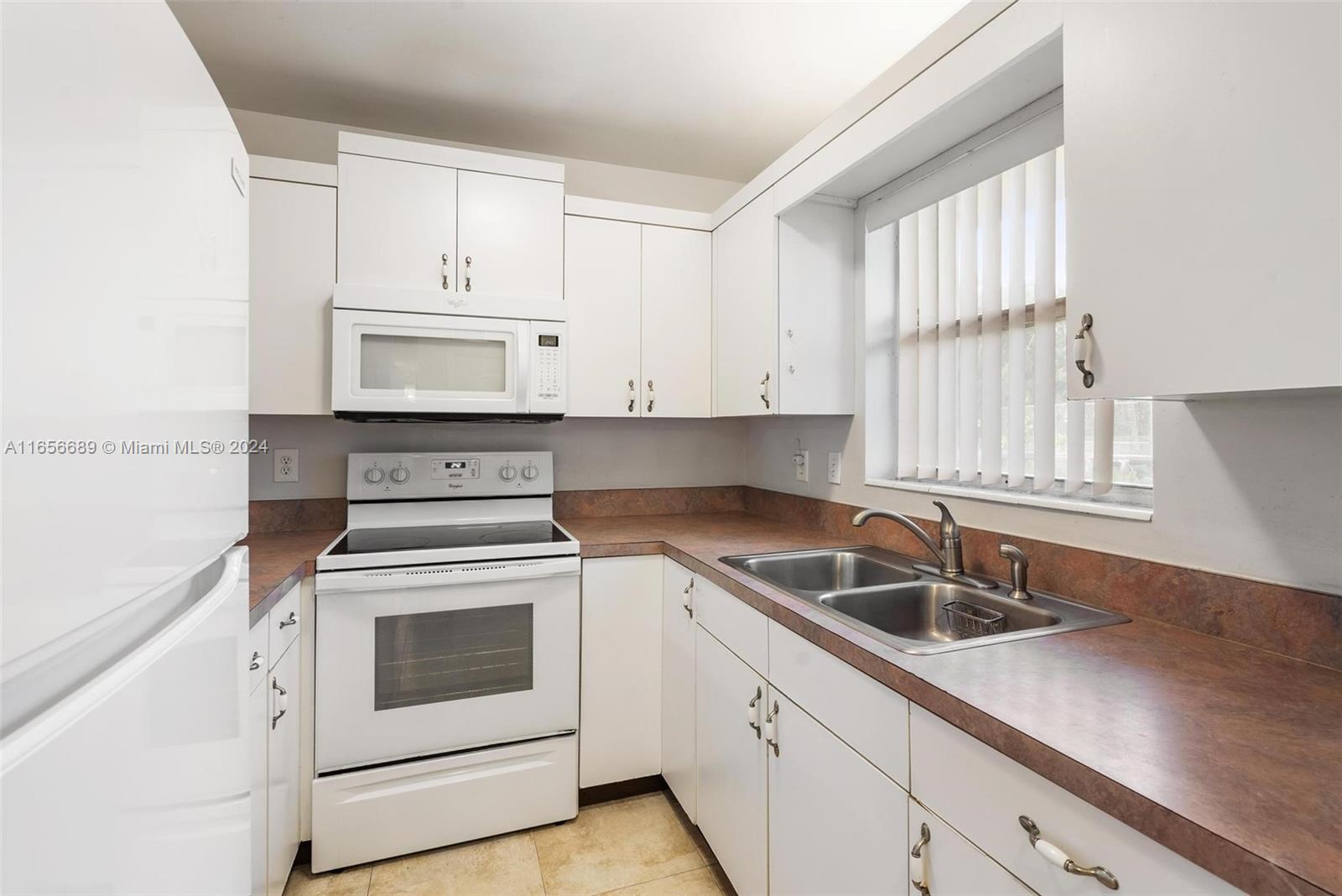 440 Southeast 2nd Avenue, Unit 3 Deerfield Beach, FL 33441 - Photo 4 of 14 a kitchen with white cabinets sink and white appliances