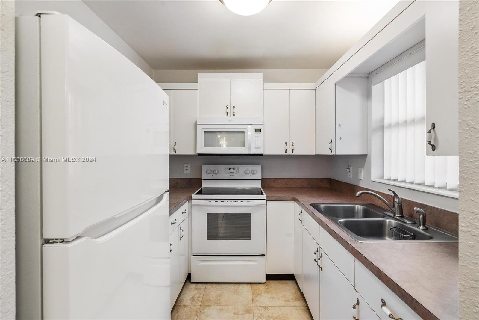 440 Southeast 2nd Avenue, Unit 3 Deerfield Beach, FL 33441 - Photo 6 of 14 a kitchen with white cabinets and white appliances