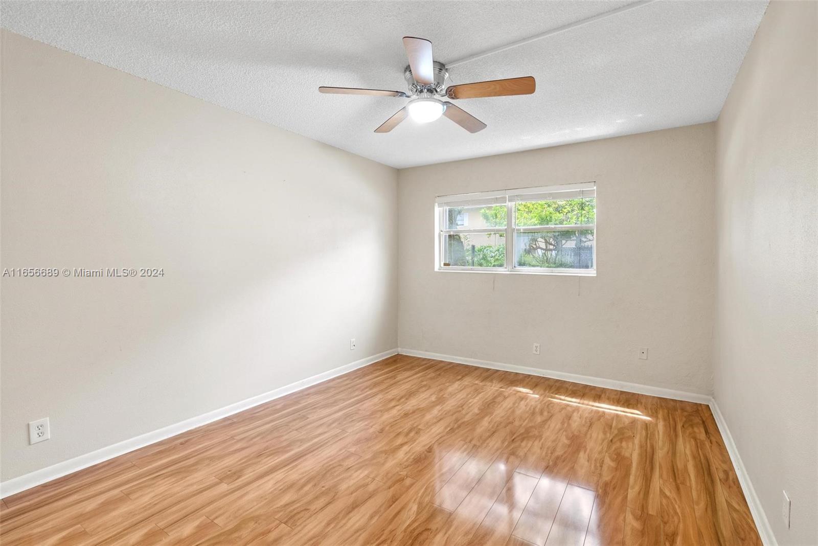 440 Southeast 2nd Avenue, Unit 3 Deerfield Beach, FL 33441 - Photo 8 of 14 an empty room with wooden floor ceiling fan and windows