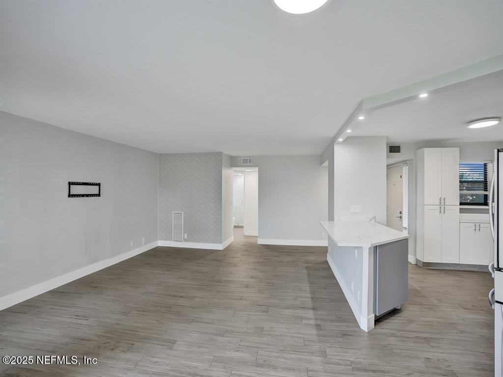 5851 Camino Del Sol, Unit 305 Boca Raton, FL 33433 - Photo 13 of 47 a view of an empty room with wooden floor and kitchen