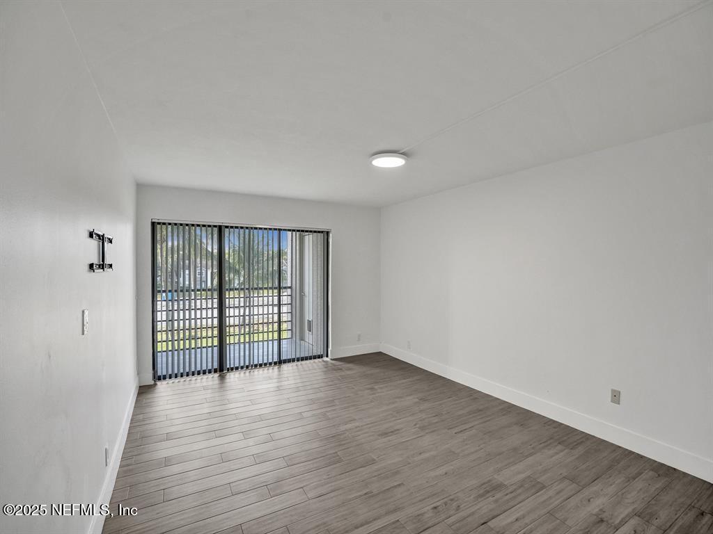 5851 Camino Del Sol, Unit 305 Boca Raton, FL 33433 - Photo 21 of 47 a view of an empty room with wooden floor and a window