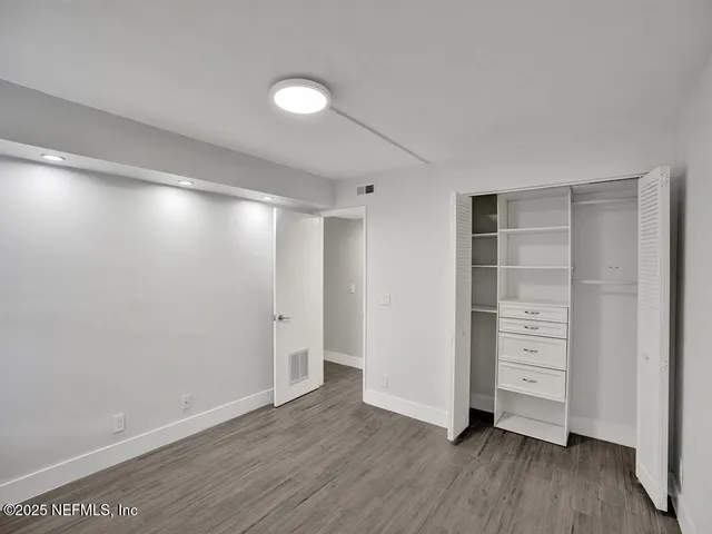 a view of an empty room with closet and wooden floor