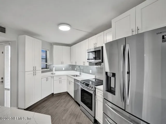 a kitchen with white cabinets and stainless steel appliances