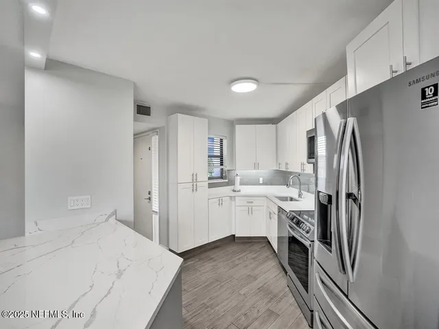 a kitchen with white cabinets and refrigerator