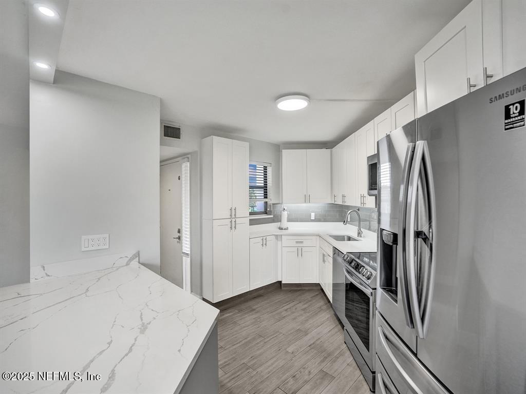 5851 Camino Del Sol, Unit 305 Boca Raton, FL 33433 - Photo 7 of 47 a kitchen with white cabinets and refrigerator
