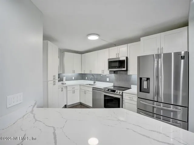 a kitchen with a sink stainless steel appliances and white cabinets