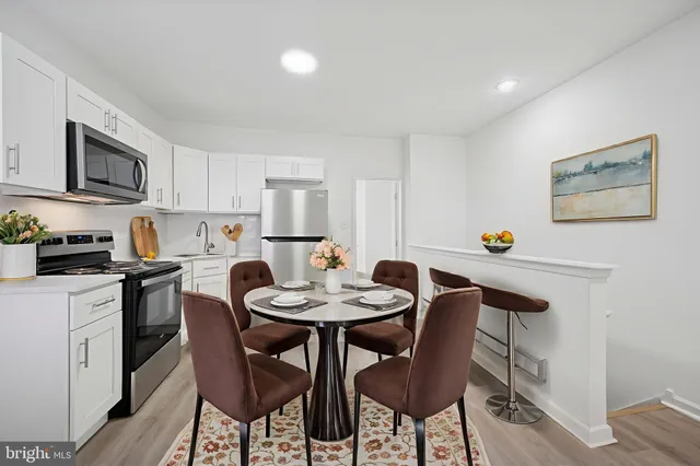 a kitchen with stainless steel appliances a dining table and chairs
