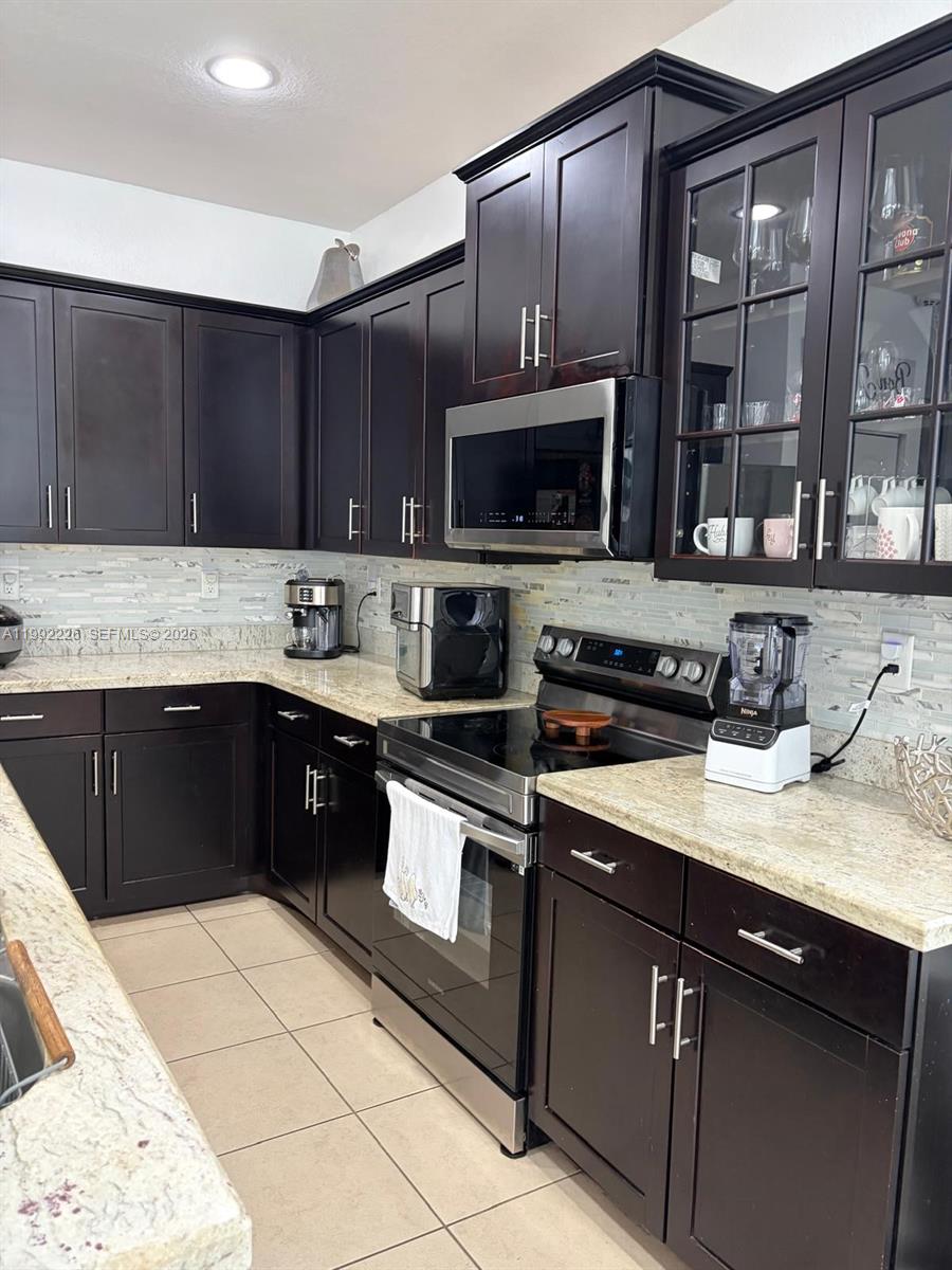 24982 Southwest 118th Court Homestead, FL 33032 - Photo 47 of 51 a kitchen with stainless steel appliances granite countertop a stove a sink and a microwave
