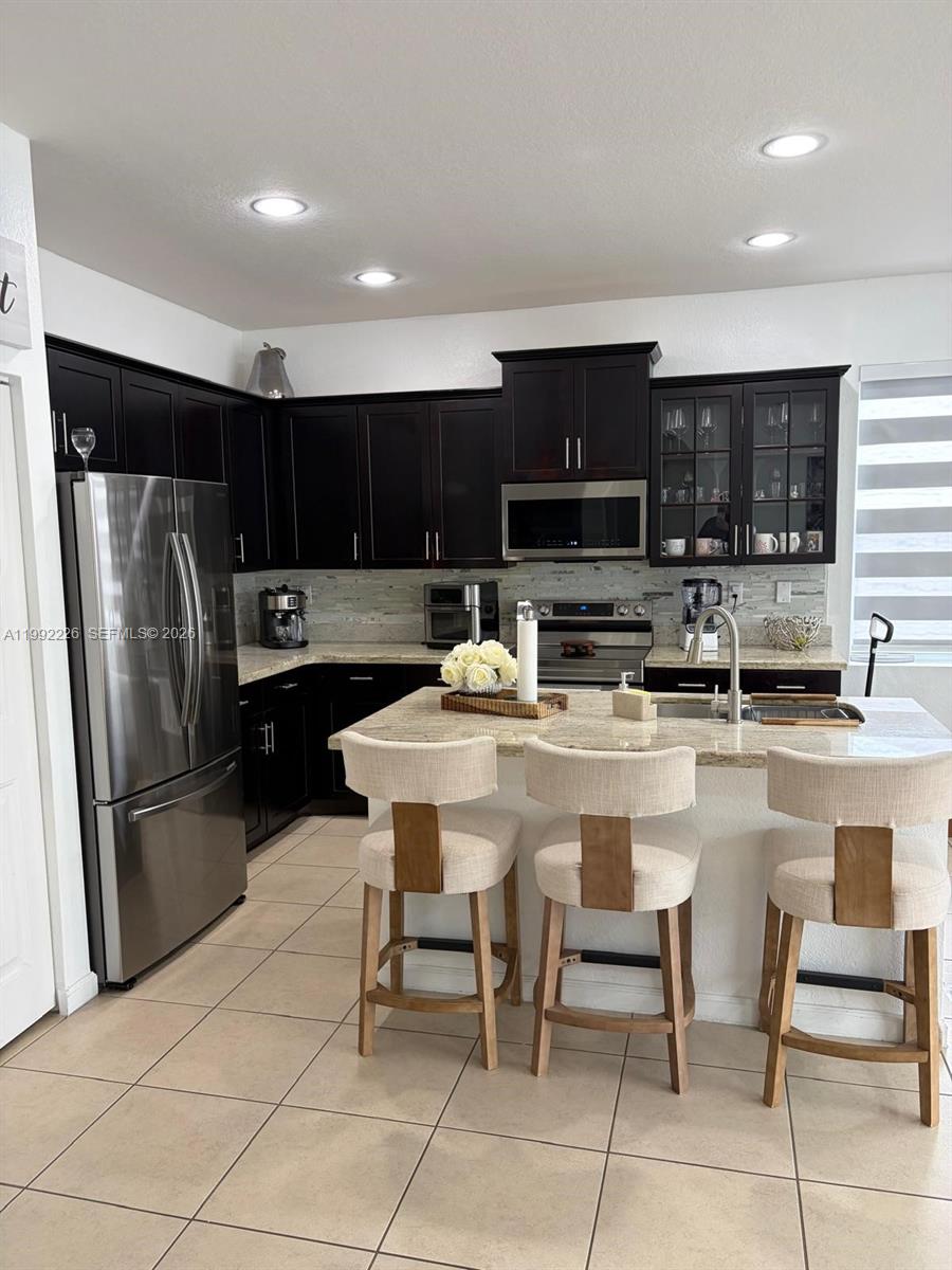 24982 Southwest 118th Court Homestead, FL 33032 - Photo 8 of 51 a kitchen with stainless steel appliances granite countertop a refrigerator a stove a sink a dining table and chairs