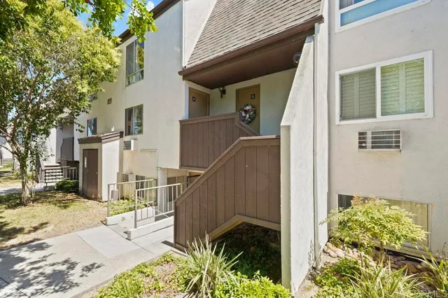 a view of a house with a wooden bench next to a road