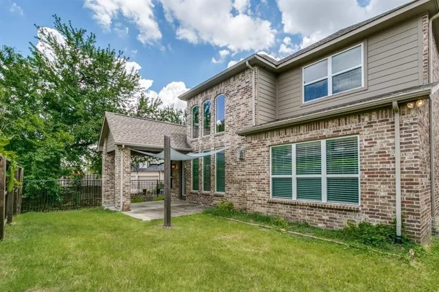 a view of a house with brick walls and a yard with a large tree