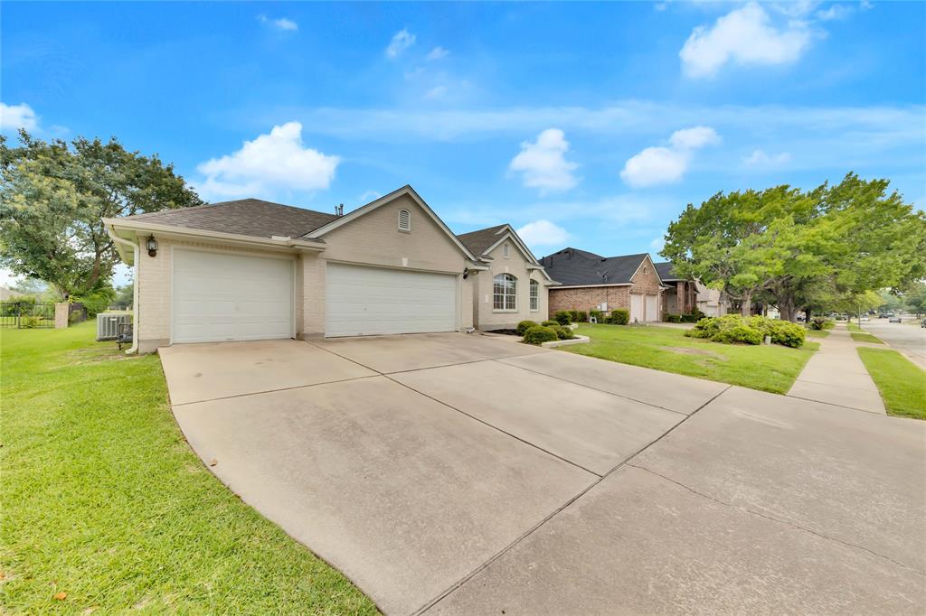 View of front of home with a front yard, a garage, concrete driveway, and brick siding
