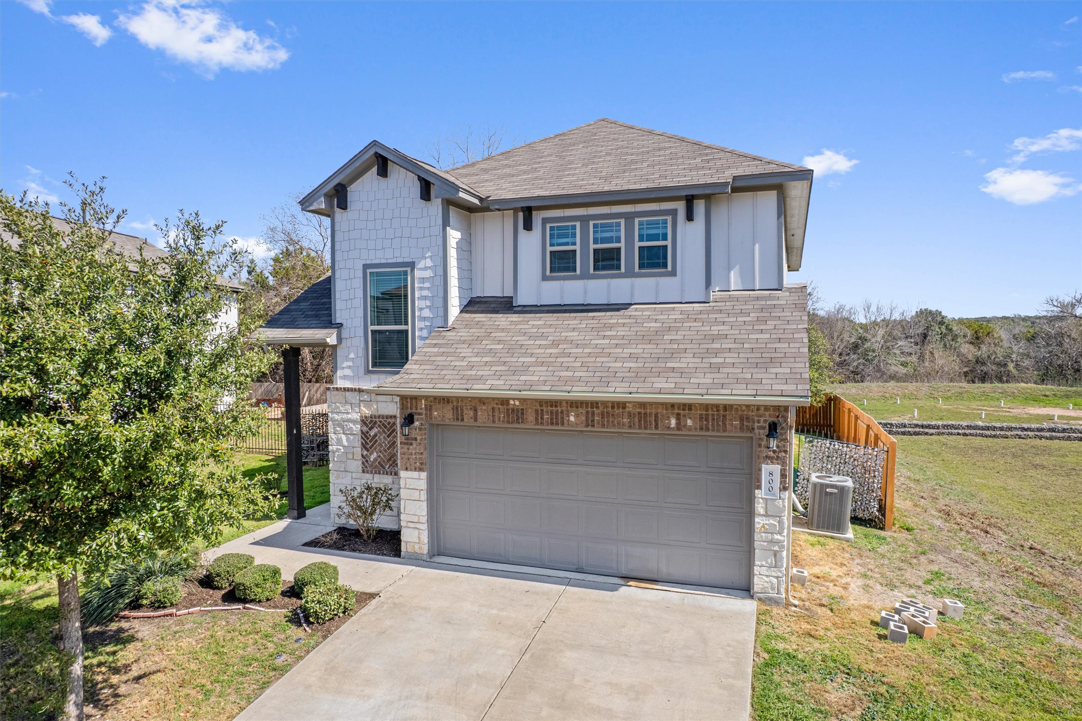 800 Totis Road Austin, TX 78748 - Photo 1 of 1 Craftsman-style house featuring board and batten siding, a shingled roof, an attached garage, concrete driveway, and stone siding