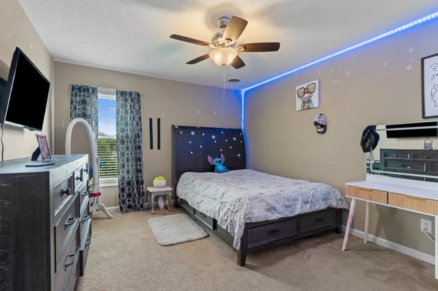 a bedroom with a bed and a flat tv screen on the dresser