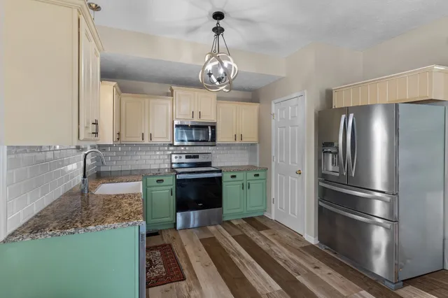 a kitchen with stainless steel appliances granite countertop a refrigerator a stove and a sink with granite countertops