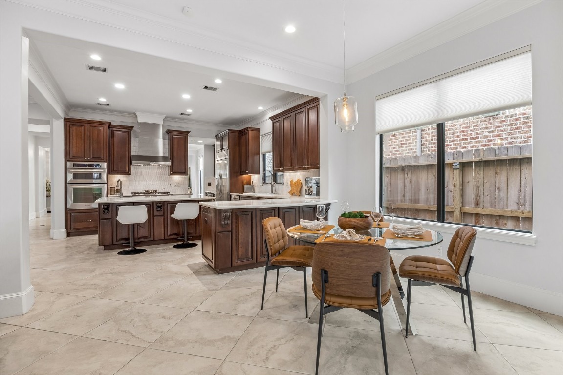 4022 Coleridge Street Houston, TX 77005 - Photo 11 of 31 Open kitchen and breakfast area featuring rich wood cabinetry, expansive marble countertops, and views of the outdoor space.