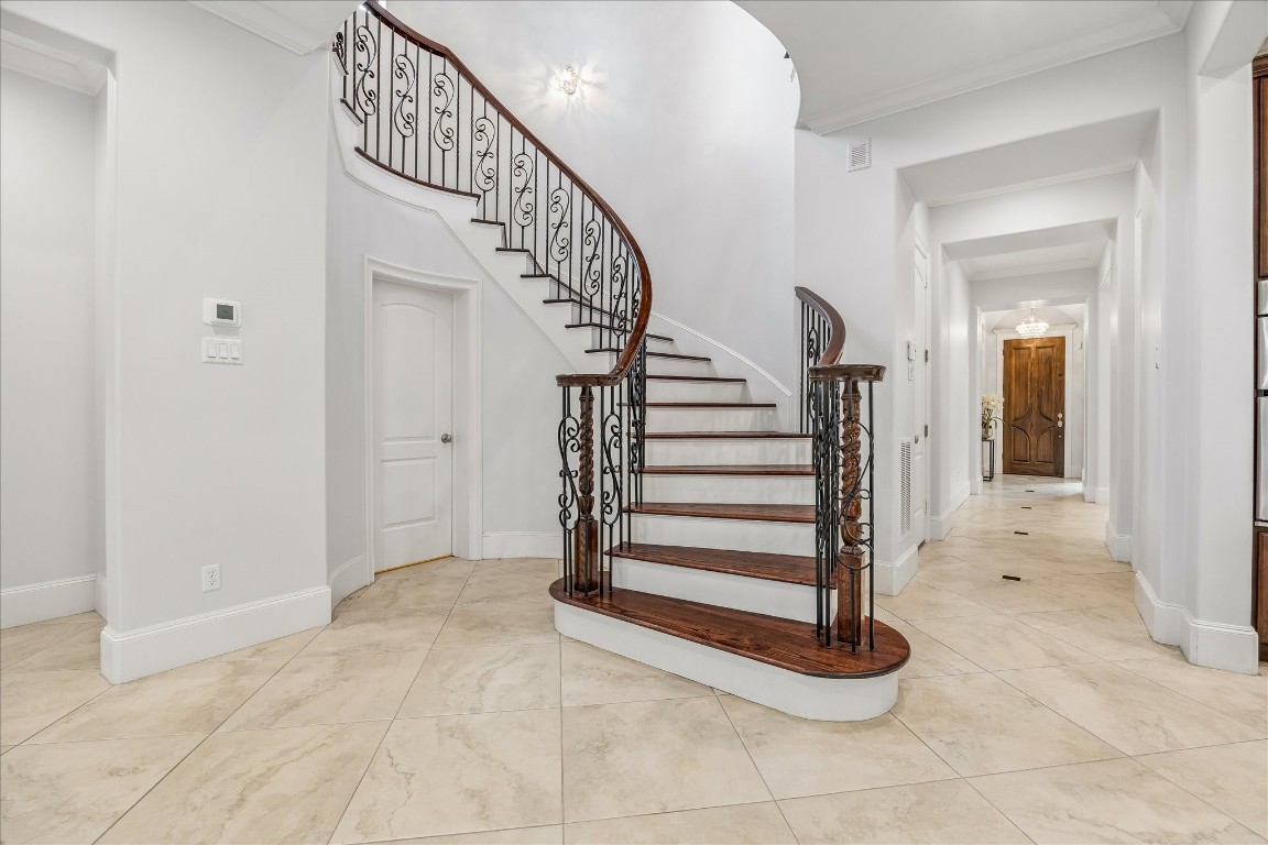 4022 Coleridge Street Houston, TX 77005 - Photo 17 of 31 Dramatic entry foyer featuring soaring ceilings, a sweeping curved staircase with wrought-iron balusters, and oversized stone flooring.