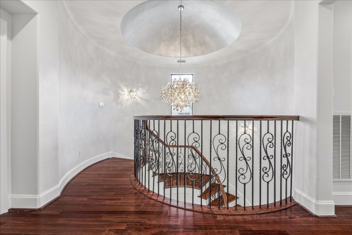 4022 Coleridge Street Houston, TX 77005 - Photo 18 of 31 Elegant second-floor landing overlooking the grand staircase with decorative wrought-iron railing and a striking designer chandelier beneath a domed ceiling.