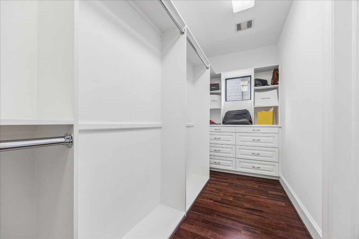 4022 Coleridge Street Houston, TX 77005 - Photo 29 of 31 Spacious walk-in primary closet featuring custom built-ins, drawer storage, and hanging space with rich hardwood flooring.