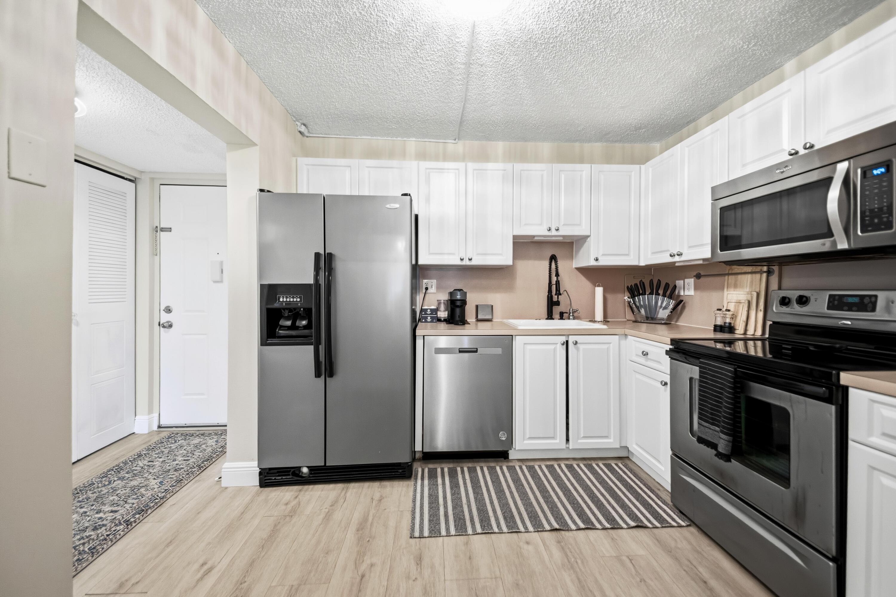 a kitchen with white cabinets stainless steel appliances and a refrigerator