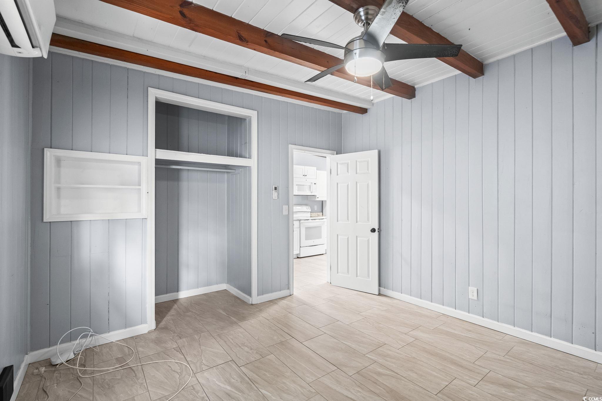 3402 Turner Street North Myrtle Beach, SC 29582 - Photo 11 of 26 Unfurnished bedroom featuring beamed ceiling, a wall mounted air conditioner, a closet, wooden walls, and ceiling fan