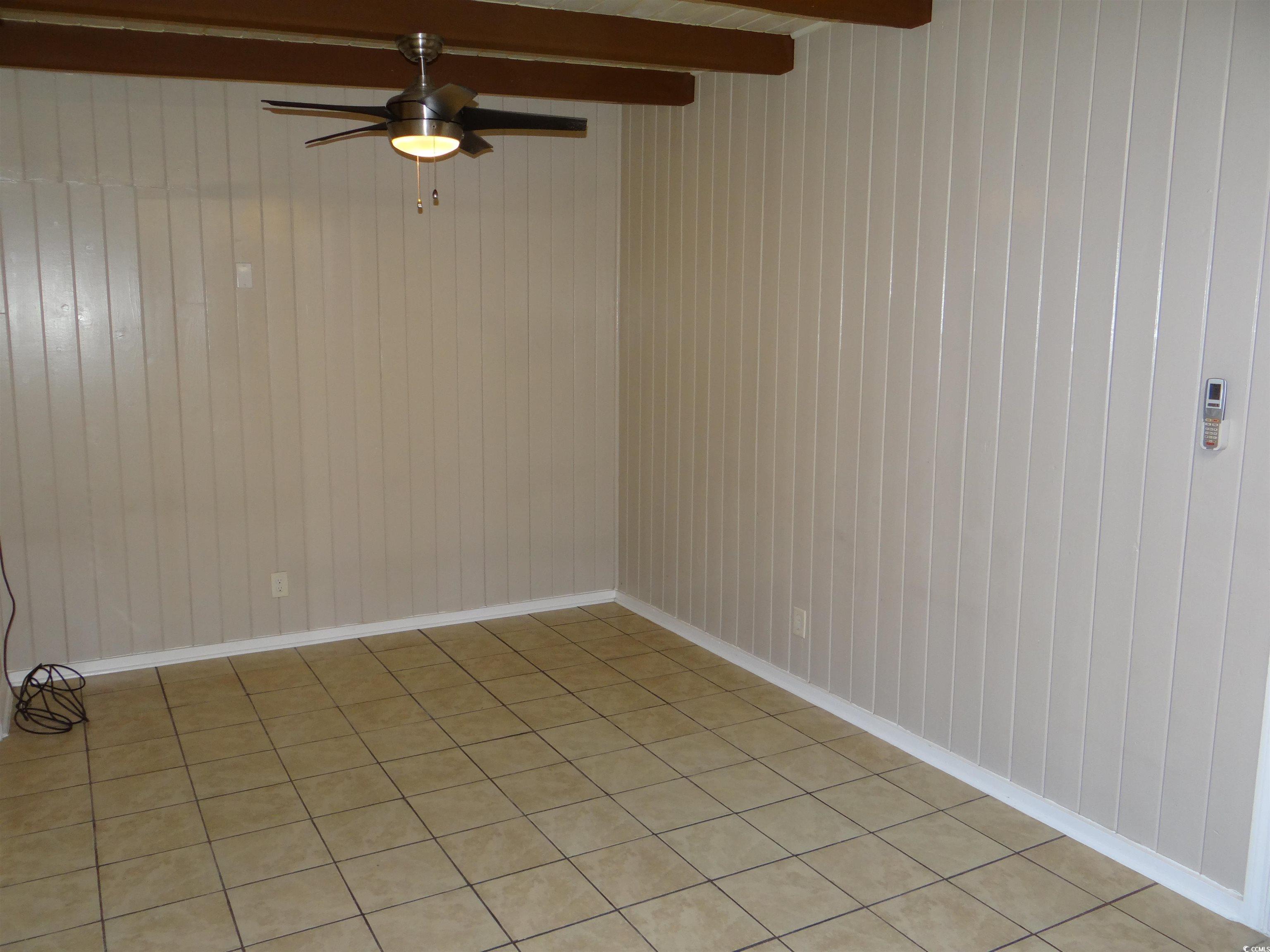 3402 Turner Street North Myrtle Beach, SC 29582 - Photo 18 of 26 Unfurnished room with a ceiling fan, beam ceiling, tile patterned flooring, and wood walls
