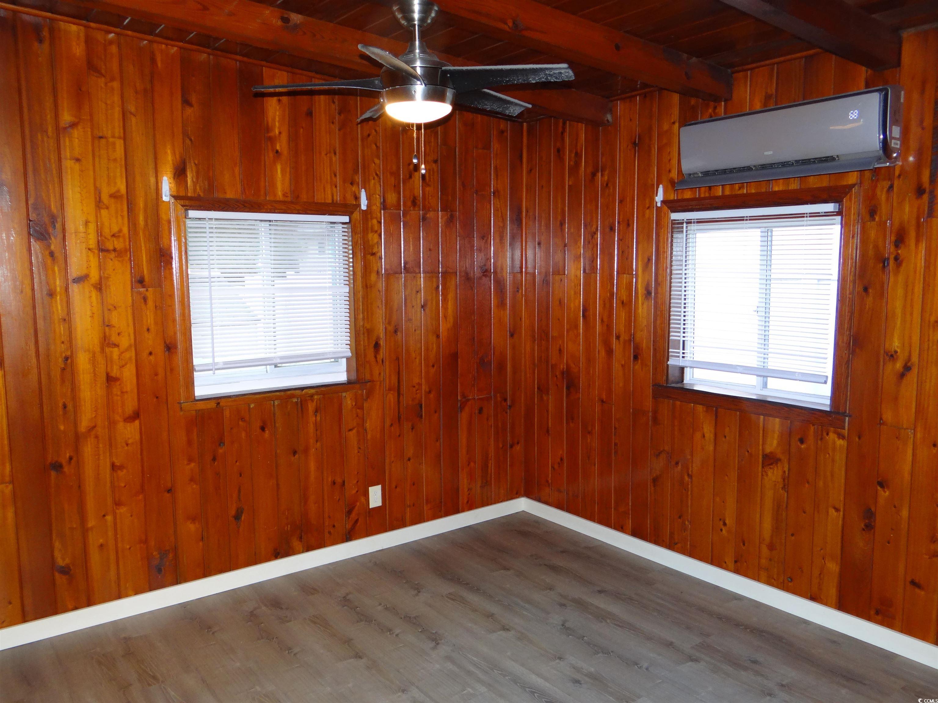 3402 Turner Street North Myrtle Beach, SC 29582 - Photo 21 of 26 Empty room with dark wood finished floors, Split Central air conditioner, healthy amount of natural light, wood walls, and a wooden ceiling with exposed beams