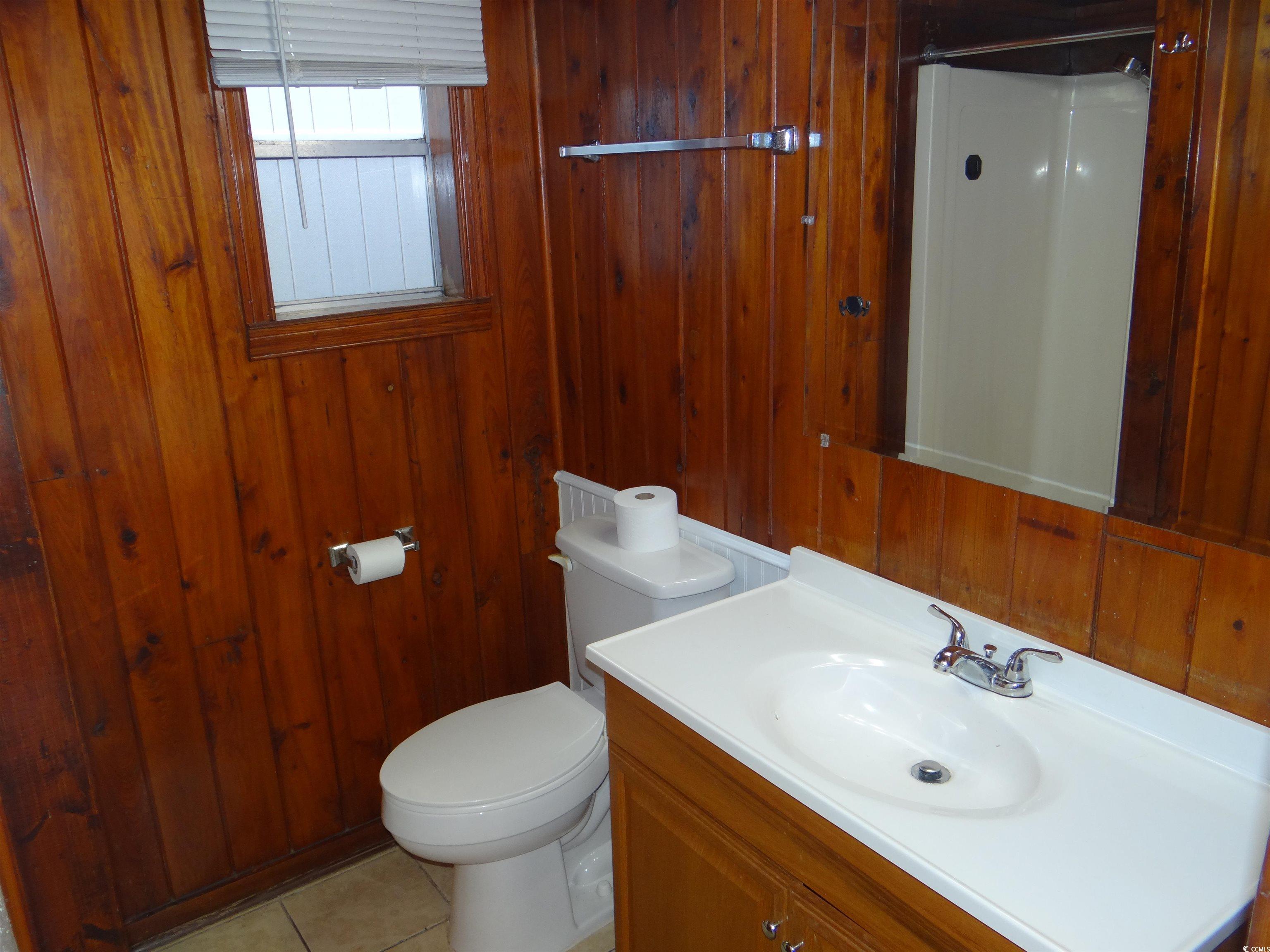 3402 Turner Street North Myrtle Beach, SC 29582 - Photo 22 of 26 Bathroom with vanity, light tile patterned floors, a shower with shower curtain, and wooden walls