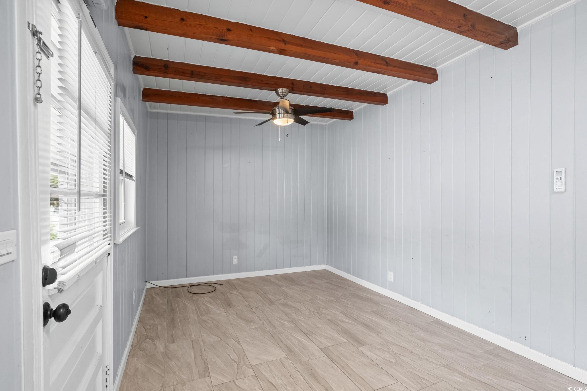 3402 Turner Street North Myrtle Beach, SC 29582 - Photo 5 of 26 Empty room featuring wooden walls, a ceiling fan, and a wood ceiling with exposed beams