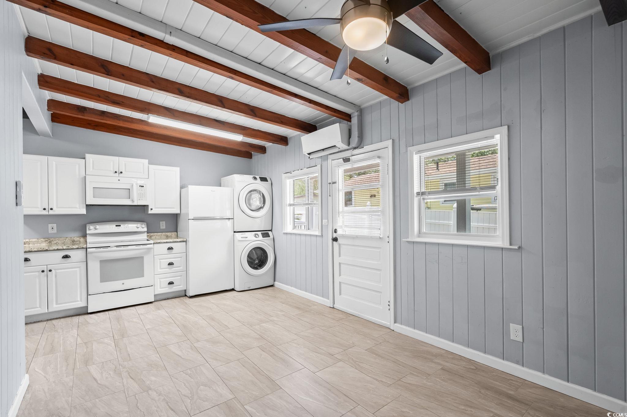3402 Turner Street North Myrtle Beach, SC 29582 - Photo 6 of 26 Kitchen with white appliances, white cabinetry, stacked washing machine and dryer, an AC wall unit, and wood walls