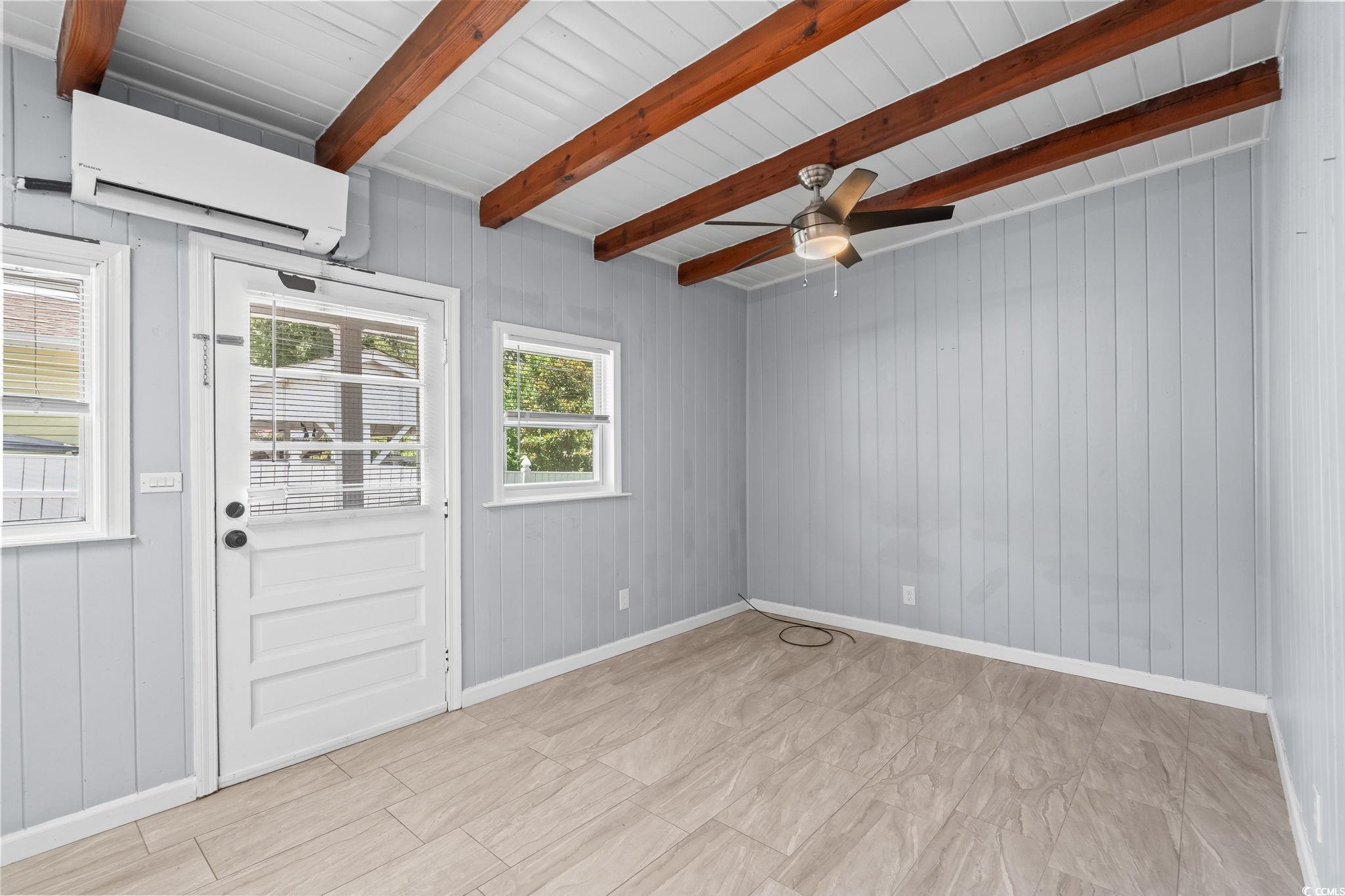 3402 Turner Street North Myrtle Beach, SC 29582 - Photo 7 of 26 Empty room with a wall mounted AC, beam ceiling, wood walls, and a ceiling fan