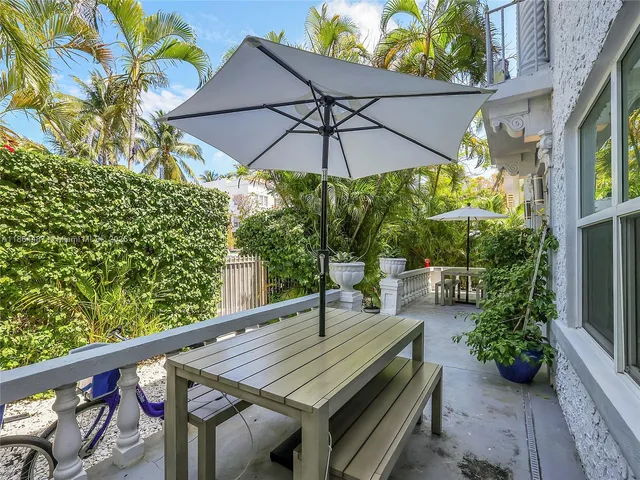 a balcony view with table and chairs under an umbrella