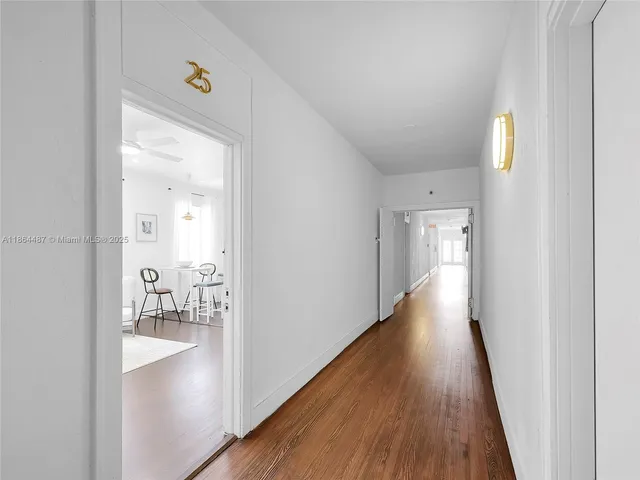 a view of a hallway with wooden floor and a bathroom