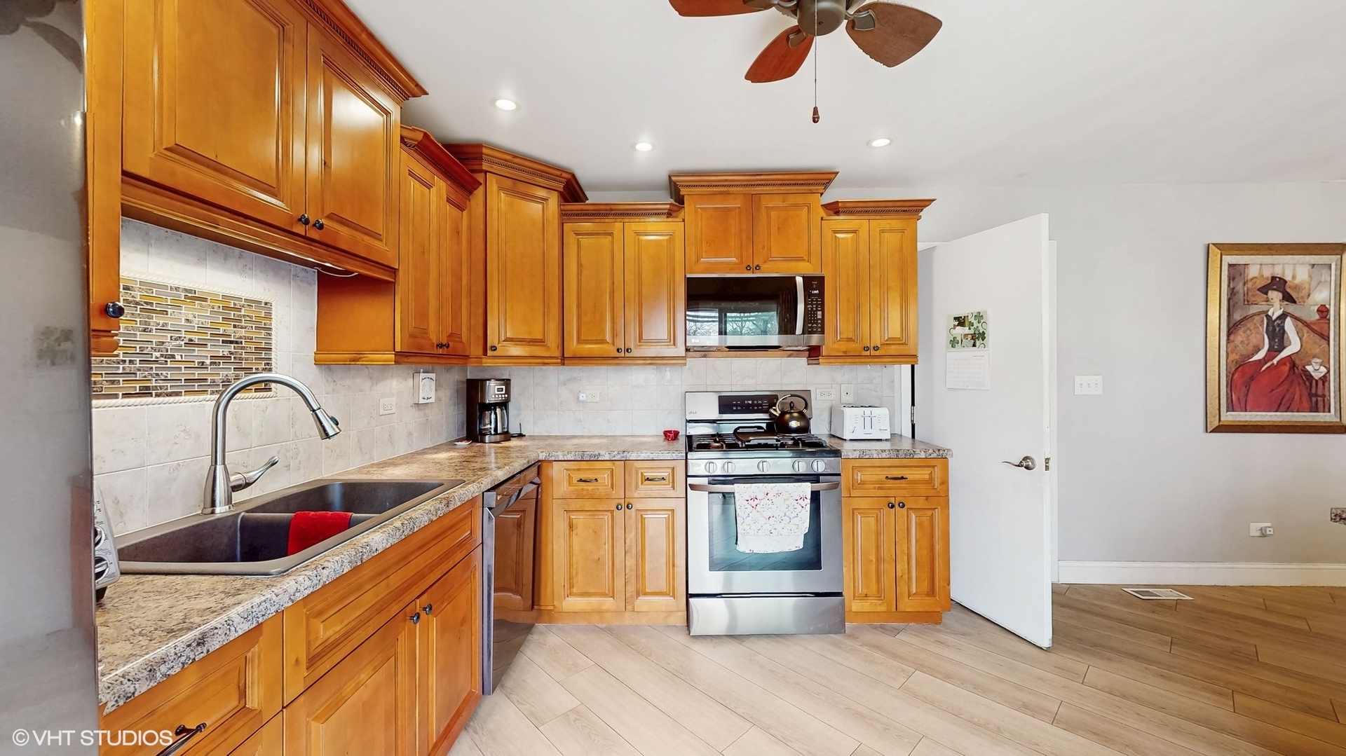 21202 Silktree Circle Plainfield, IL 60544 - Photo 8 of 25 a kitchen with stainless steel appliances granite countertop a sink a stove top oven a chimney cabinets and wooden floor