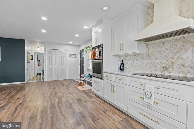 a hallway with white cabinets and wooden floor