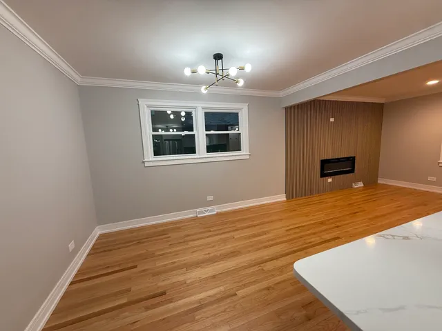 a view of an empty room with wooden floor and a ceiling fan