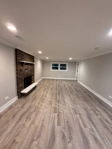 a view of an empty room with wooden floor and a fireplace