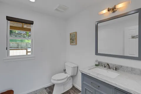 a bathroom with a granite countertop toilet sink and mirror