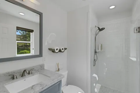 a bathroom with a granite countertop sink toilet and shower