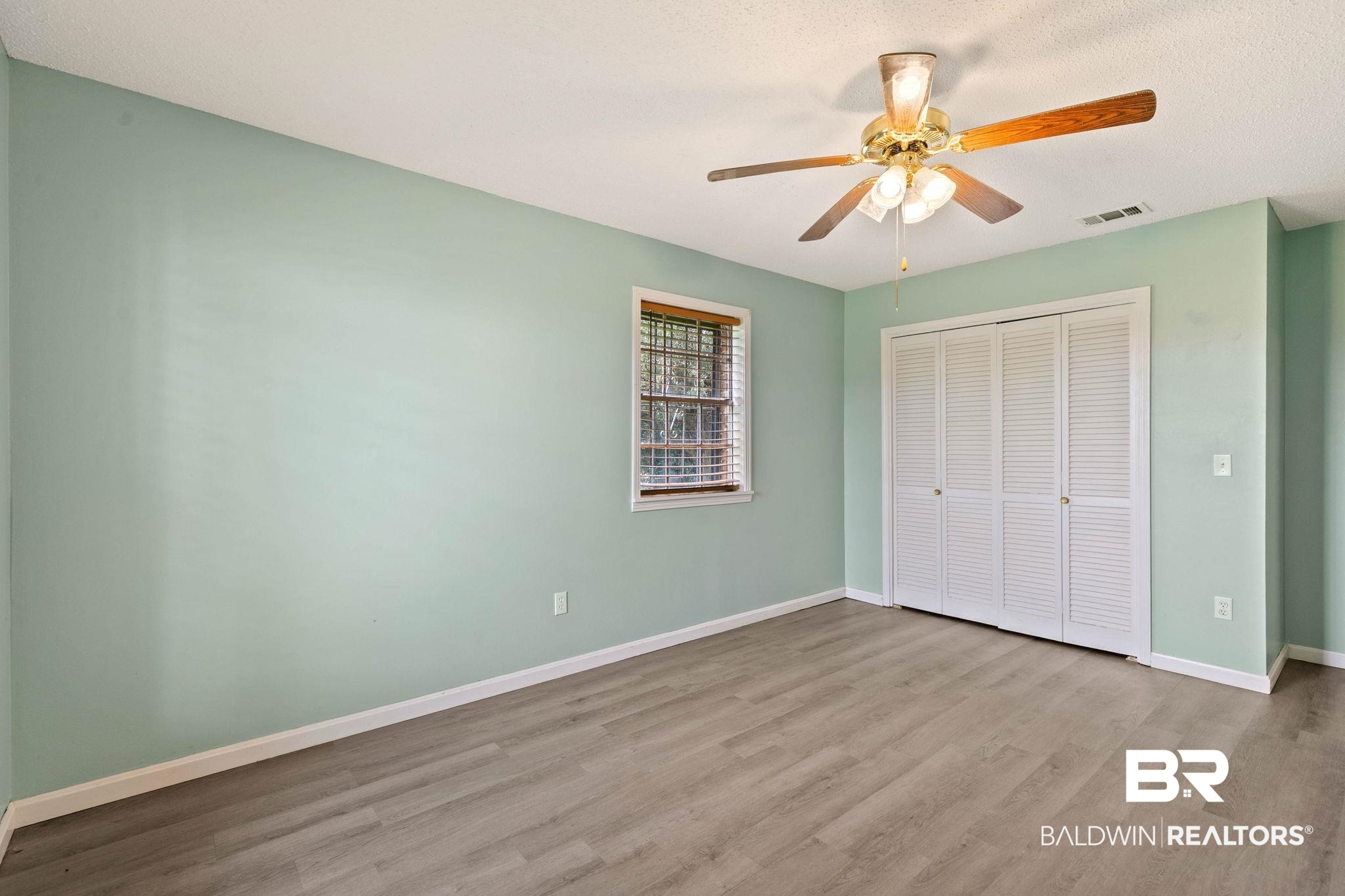 3791 Robinsonville Road Atmore, AL 36502 - Photo 32 of 55 Room featuring light wood-finish flooring, a ceiling fan with integrated lighting, a window with horizontal blinds, and louvered bifold closet doors