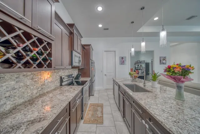 a kitchen with stainless steel appliances granite countertop a sink a stove and a wooden cabinets