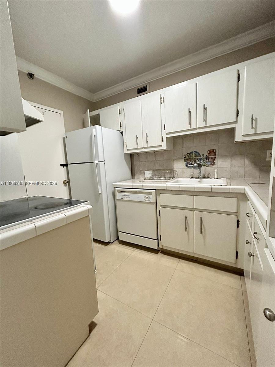 100 Lincoln Road, Unit 1010 Miami Beach, FL 33139 - Photo 5 of 12 a kitchen with a sink a stove a refrigerator and white cabinets
