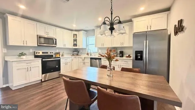 a kitchen with granite countertop a refrigerator a sink dishwasher a dining table and chairs with wooden floor